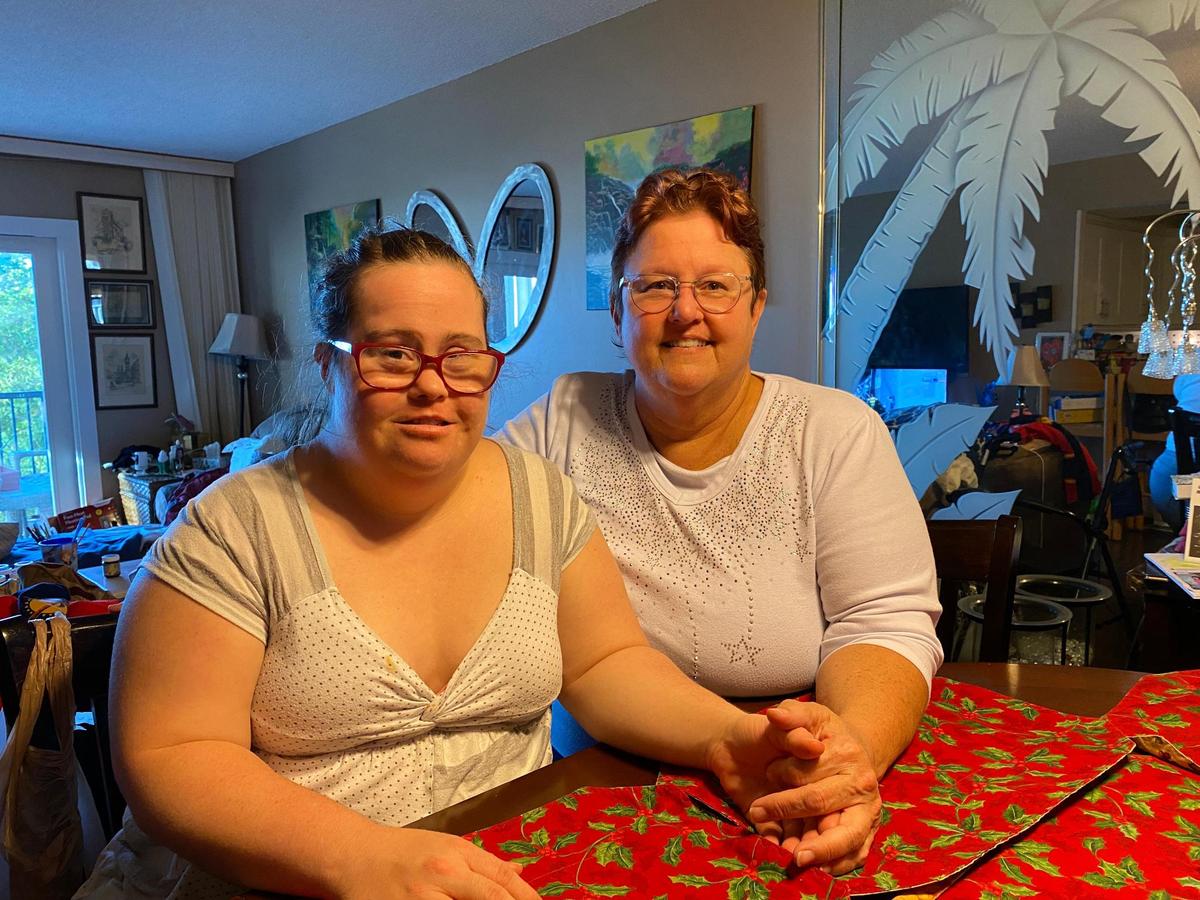 Taylor Quinones (left) and her mother, Tonya Morrison (right) sit at the kitchen table in their Pompano Beach apartment. For Quinones, who has Down syndrome, a swim with dolphins could be therapeutic and provide some cheer.