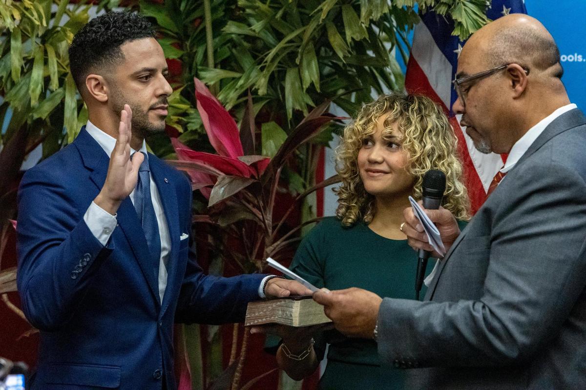 Fort Lauderdale, FL- January 18, 2023 - Newly appointed Broward County School Board Member Daniel P. Foganholi, left, is sworn in by Attorney Levi G. Williams Jr., right, as Mrs. Alyssa Foganholi, center, holds the family bible during a special ceremony at the Kathleen C. Wright Administration Center in Fort Lauderdale, Florida.
