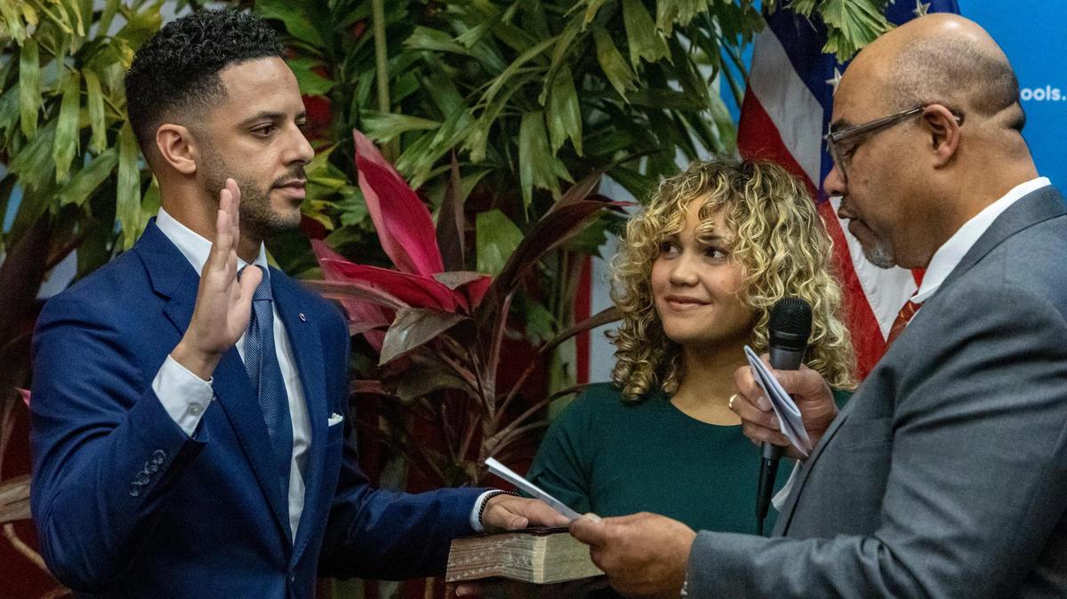 Newly appointed Broward County School Board Member Daniel P. Foganholi, left, is sworn in by Attorney Levi G. Williams Jr., right, as Alyssa Foganholi, center, holds the family Bible during a special ceremony at the Kathleen C. Wright Administration Center in Fort Lauderdale, Florida, on Jan. 18, 2023.