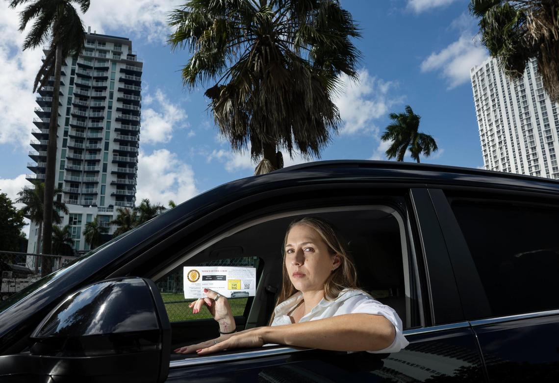 Jennifer Gonzalez holds her traffic violation notice inside her car on Friday, Feb. 21, 2025, in Miami, Fla. Gonzalez received a $225 ticket from the Miami-Dade Police Department after it was issued by BusPatrol for what they claim was illegally passing a school bus. She was one of over 250 Miami-area drivers who reached out to the Miami Herald to say they received school bus stop arm tickets in error.