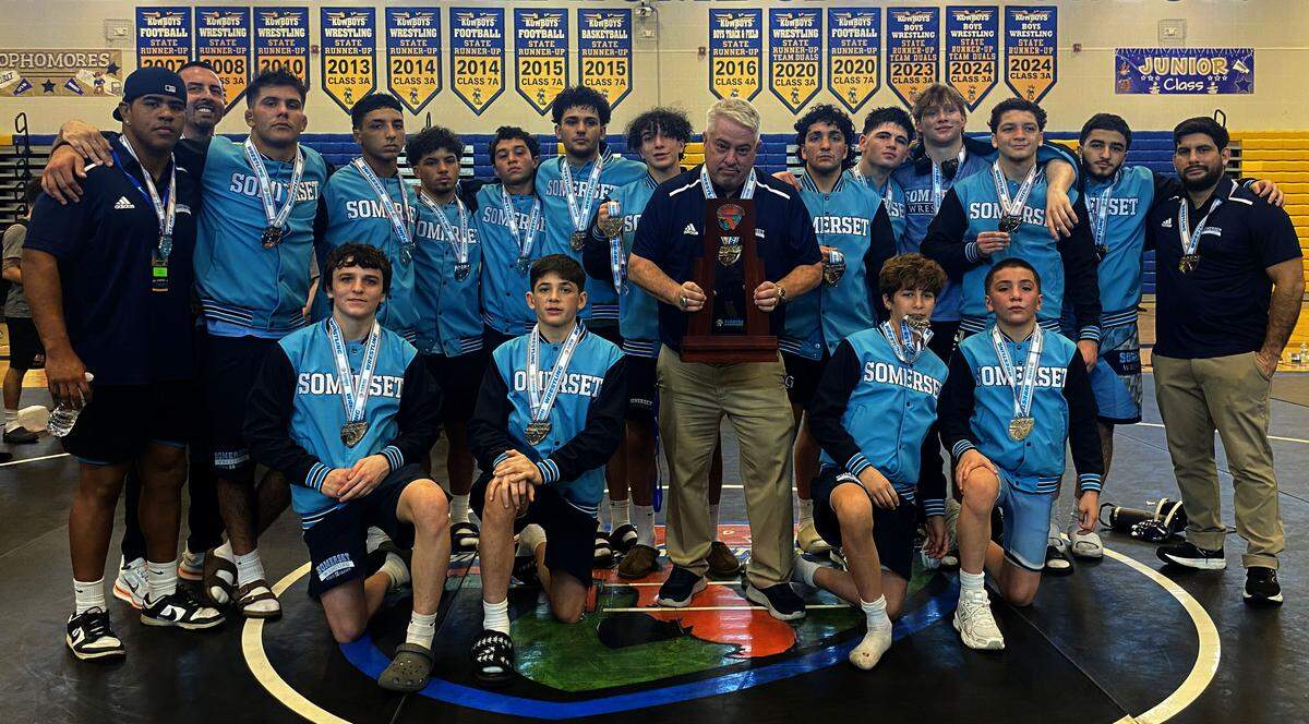 Somerset Academy wrestlers and coaches huddle together with the state runners-up trophy after finishing second at the 2A Duals wrestling state championships on Saturday at Osceola High School in Kissimmee.