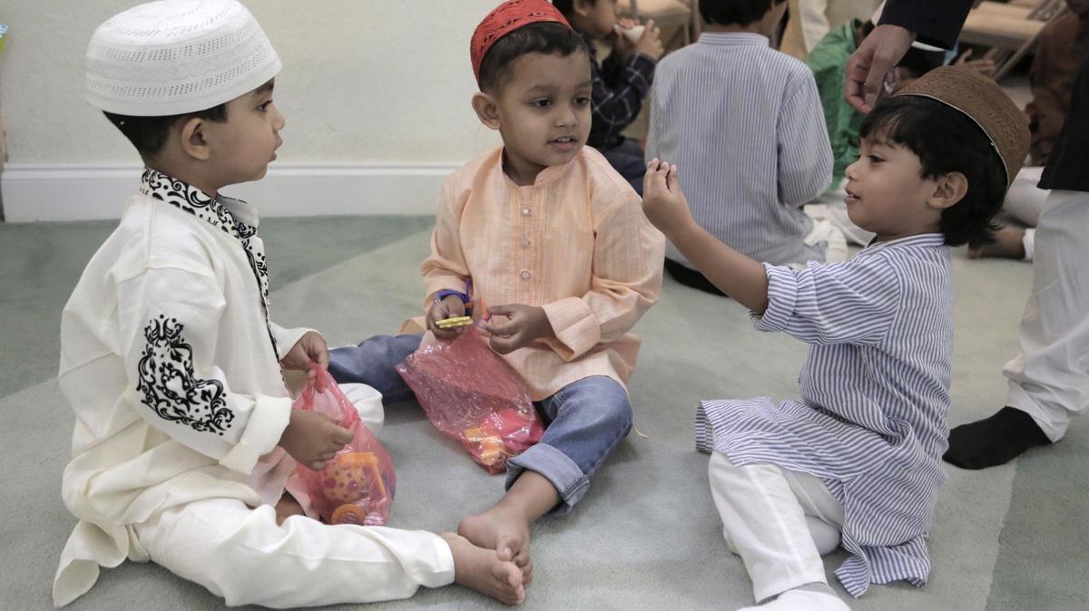 Faris Ahmed, Talha Ahmed and Zying Budan enjoy gifts given to them after the prayer service at a Hallandale Beach mosque.