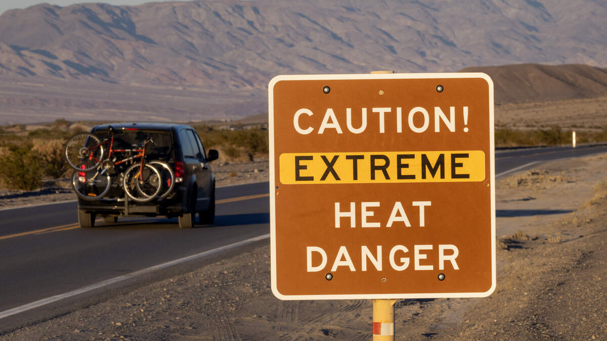 A car passes a sign warning of extreme heat danger on the eve of a day that could set a new world heat record in Death Valley National Park on July 15, 2023 near Furnace Creek, California.