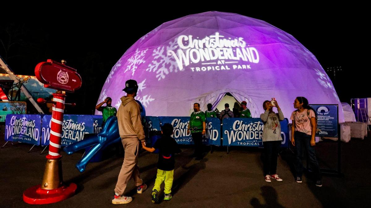 Asistentes llegan al IG'loo 360-Dome para ver una aventura de inmersión en mapas 3D, durante la noche de inauguración de Christmas Wonderland en el Tropical Park, en Miami, el viernes 17 de noviembre de 2023.