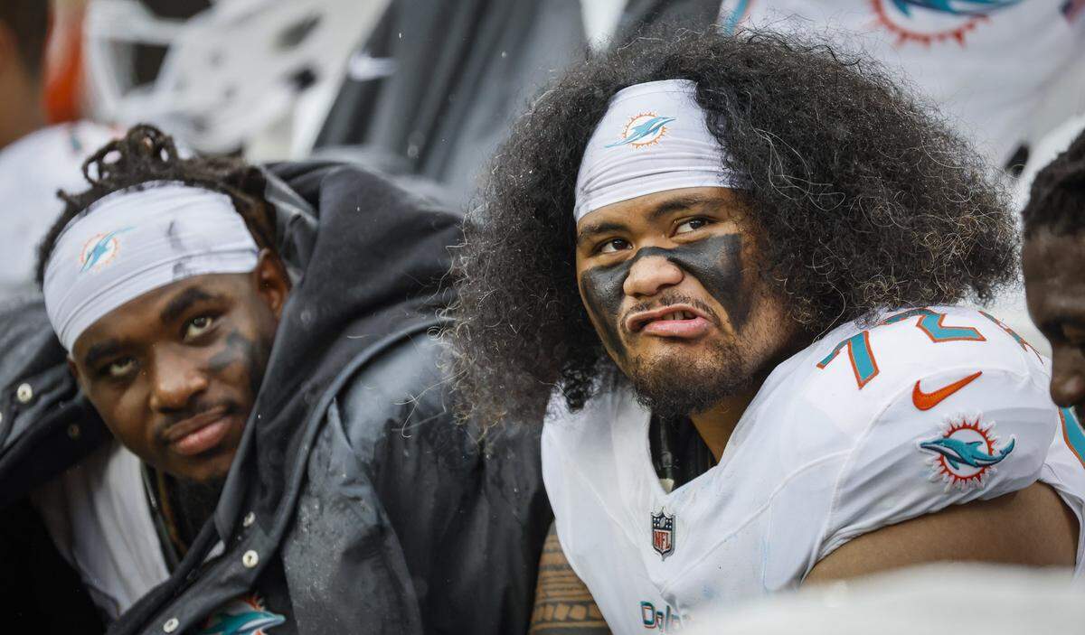 Miami Dolphins center Aaron Brewer (55) and offensive tackle Jonah Savaiinaea (72) watch the game action on the big screen as the Dolphins trail the Cleveland Browns during the first half of an NFL football game at Huntington Bank Field in Cleveland, Ohio, on Sunday, October 19, 2025. 