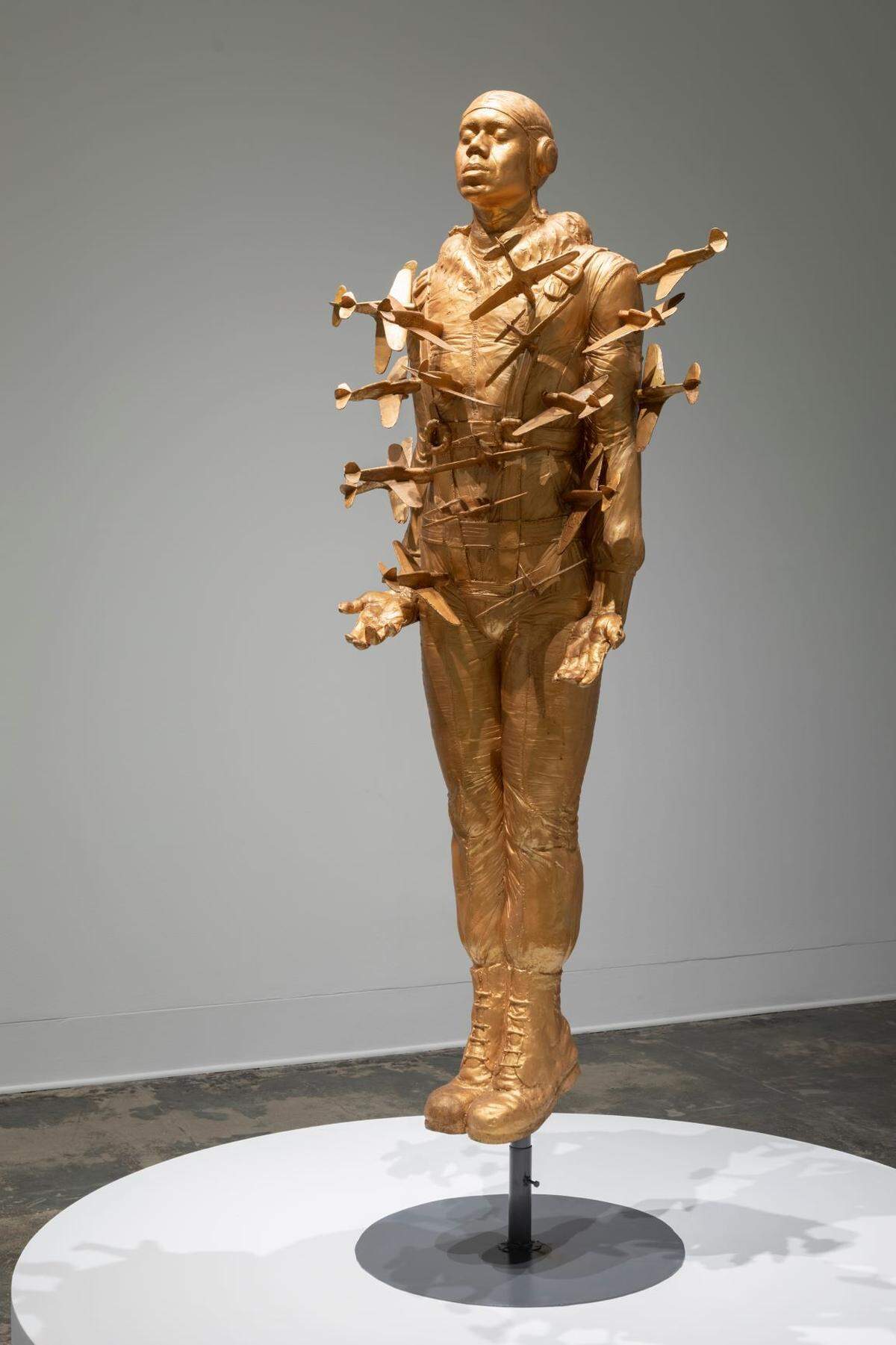 Tar Baby vs. St. Sebastian” (1999) depicts a life-sized likeness of Richards as a Tuskegee airman impaled by miniature planes and is part of his “Tuskegee Airmen Collection” that he spent over a decade creating. The analogy is to St. Sebastian, who was executed by being shot full of arrows for protecting captured Christians he was supposed to imprison.