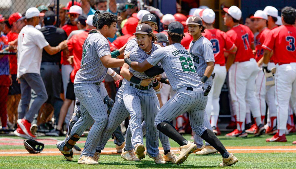 Varela Varsity Vipers Sebastian Gonzalez (12) is held back by teammates during an incident involving fans during the game against Doral Firebirds in the third inning at Doral Academy in Doral on Saturday, May 13, 2023.
