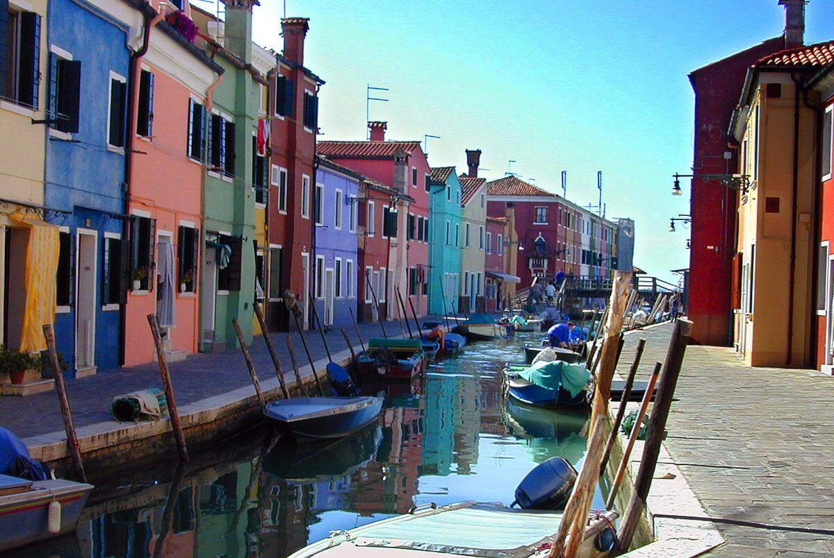 The colorful streets of the island of Burano, known for its lace, a craft that evolved centuries ago from the skill of fishermen’s wives at mending nets.