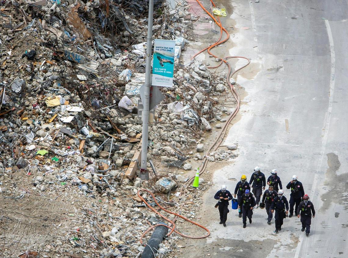 A rescue team walks past rubble on the side of the Champlain South Towers condo that was imploded, in Surfside, Florida on July 13, 2021.
