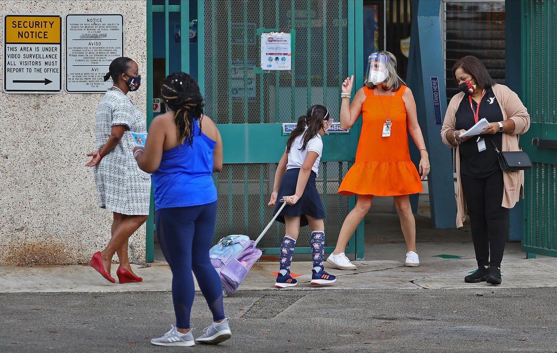Parents drop off their children at Henry S. Laboratory School, where more than a majority of parents elected to send their children to school as members of the staff greet them on Monday, October 5, 2020.