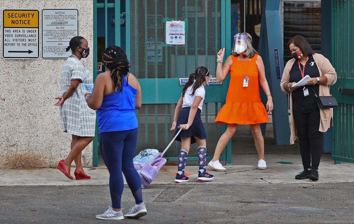 Parents drop off their children at Henry S. Laboratory School, where more than a majority of parents elected to send their children to school as members of the staff greet them on Monday, October 5, 2020.