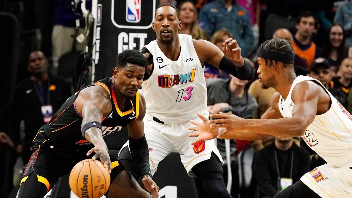 Phoenix Suns center Deandre Ayton, left, tries to control the ball in front of Miami Heat center Bam Adebayo (13) and forward Jimmy Butler, right, during the first half of an NBA basketball game in Phoenix, Friday, Jan. 6, 2023.