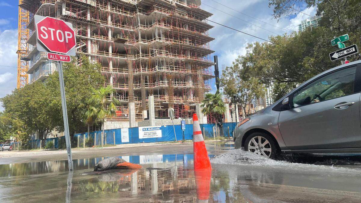 A driver crosses a flooded intersection on Southwest Third Avenue and Southwest Sixth Street near the Jose Marti Park in Miami on Feb. 5, 2023.