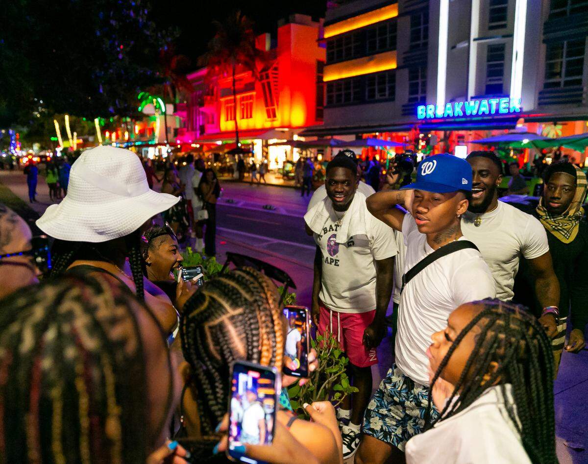 People visit Ocean Drive near 10th Street in Miami Beach, Florida on Friday, March 25, 2022. City officials imposed a midnight curfew and forced stores to stop selling alcohol after 6 p.m. The restrictions were set in place after two shootings in Miami Beach the weekend before caused city officials to announce a “state of emergency.”