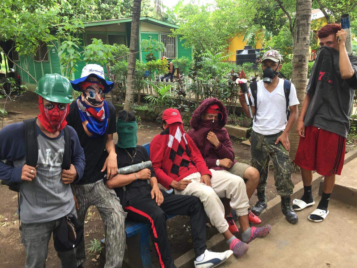 Young men from the San Judas neighborhood near the National Autonomous University of Nicaragua visit the campus to rest after guarding roadblocks in streets surrounding the campus. They carry homemade mortars, which are tubes loaded with a projectile and explosive propellant.