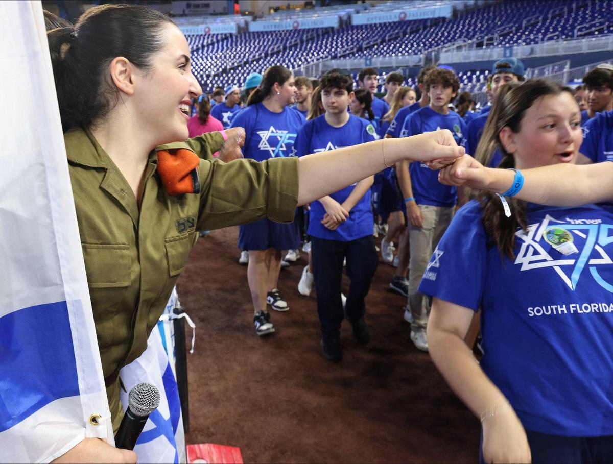 Israeli Defense Forces soldier Natalia Levi, left, fist-bumps students as they parade into the ballpark. On Wednesday, April 26, 2023, the South Florida community celebrated Israel’s 75th Independence Day.