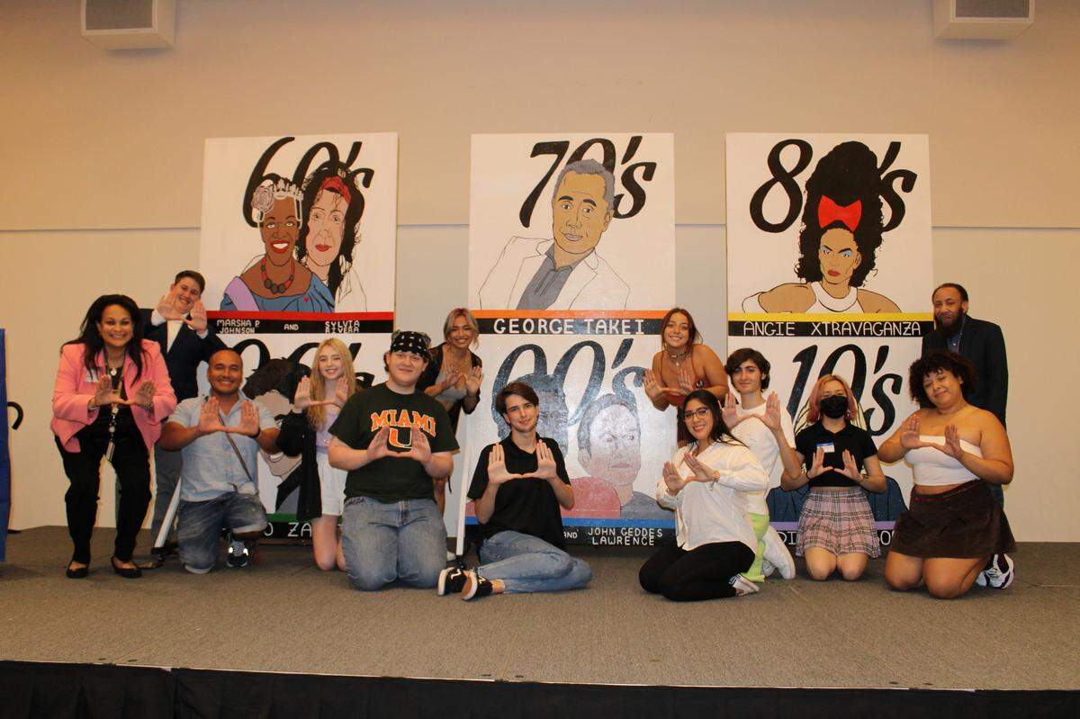 Dr. Gisela P. Vega, director of the LGBTQ Center at the University of Miami, and her students take a photo in front of their LGBTQ mural.