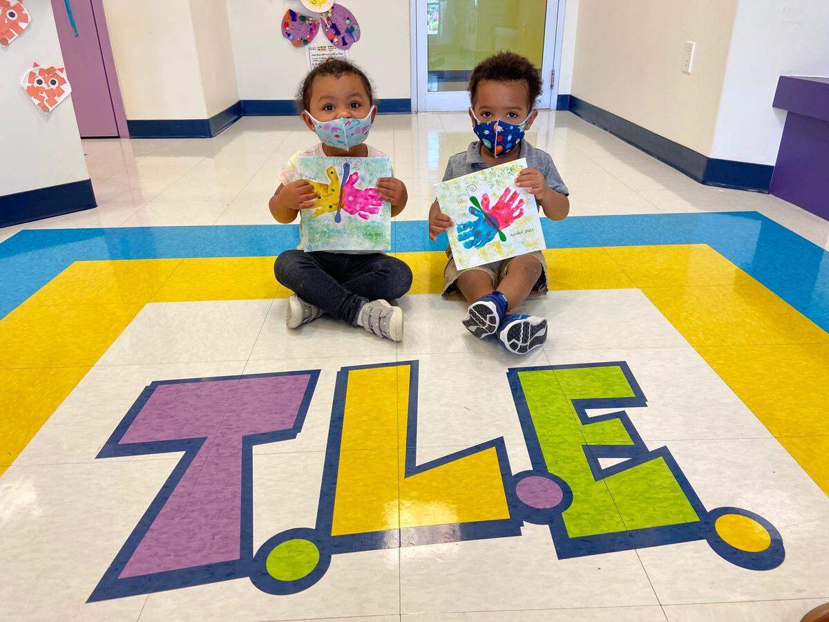 Preschoolers Leah Naylor and Xander Caddler pose with their artwork for the Art For Wishes fundraiser.