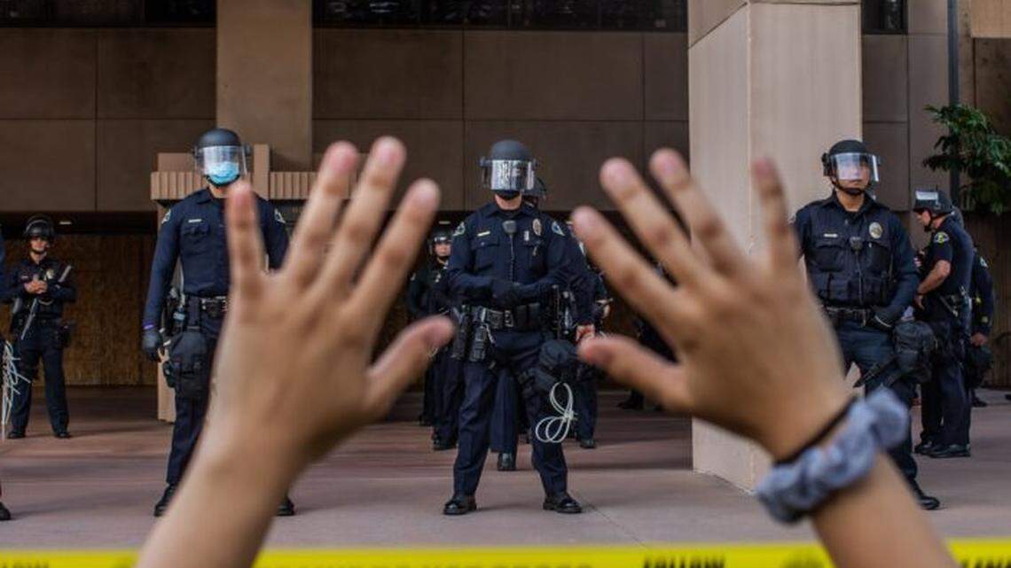A demonstrator holds her hands up while she kneels in front of police in Anaheim, California, during a peaceful protest over the death of George Floyd.