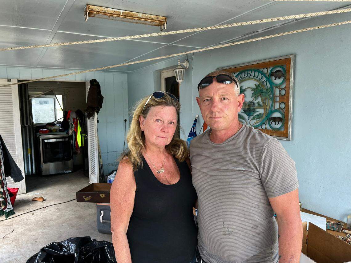 Anne McDougall, 64, and Marvin Kitrell, pose in front of McDougall’s flooded home in Fort Lauderdale. Kitrell’s home saw less flooding so he’s been helping his neighbors, like McDougall, clean up.