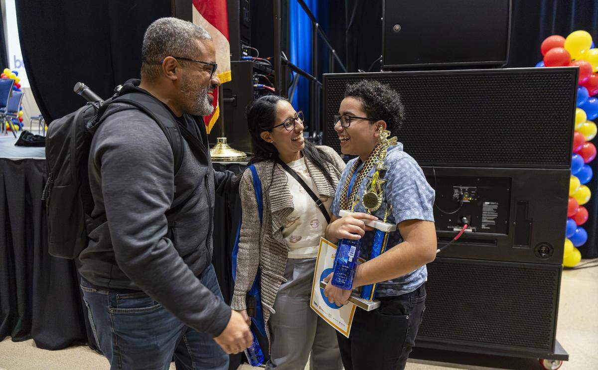 Logan Cox, an eighth grader from Herbert A. Ammons Middle School, is congratulated by his mother, Janet Carballo, and his father, Adam Cox, after he won the 86th Miami Herald Spelling Bee for Miami-Dade and Monroe County at the Charles F. Dodge City Center on Wednesday, Feb. 25, 2026, in Pembroke Pines, Fla.