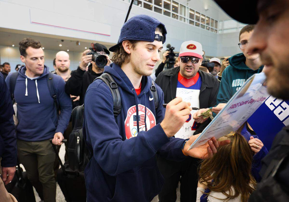 Jack Hughes of the United States, signs autographs for fans upon arrival at Miami International Airport on Monday, Feb. 23, 2026, in Miami, after returning from Milan following the Americans' gold-medal victory over Canada at the 2026 Winter Olympics in Milano Cortina, Italy.