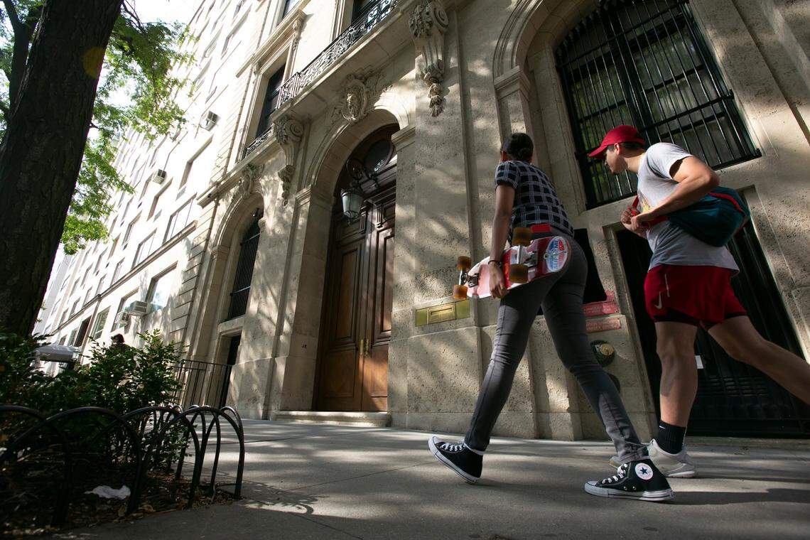 People walk by the Upper East Side New York estate of mulitmillionaire Jeffrey Epstein. Damage on the front doors of Epstein’s residence was caused by agents serving a search warrant following Epstein’s arrest at a nearby New Jersey airport Saturday July 6, 2019 . Epstein has been charged with sex trafficking of minors in New York and Palm Beach, Fl. and remains behind bars awaiting a bond hearing.