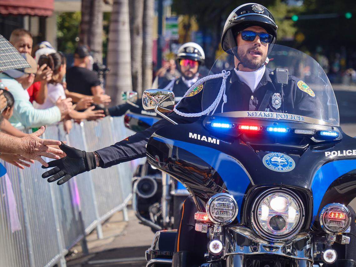 Members City of Miami Police motorcade each to greet the crowd with an extended hand while riding in the Three Kings Parade. 
