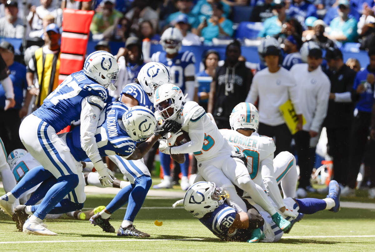 Miami Dolphins running back De'Von Achane (28) is brought down by Indianapolis Colts safety Nick Cross (20), cornerback Kenny Moore II (23), and cornerback Mekhi Blackmon (29) during the first half of an NFL game at Lucas Oil Stadium on Sunday, September 7, 2025, Indianapolis, Indiana.