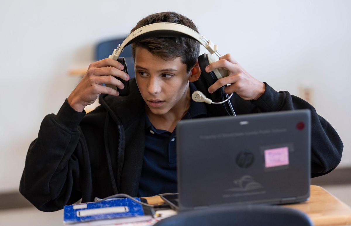 Alexandr Mokryk, 13, from Ukraine, puts on headphones in his ESOL class at Aventura Waterways K8 Center.