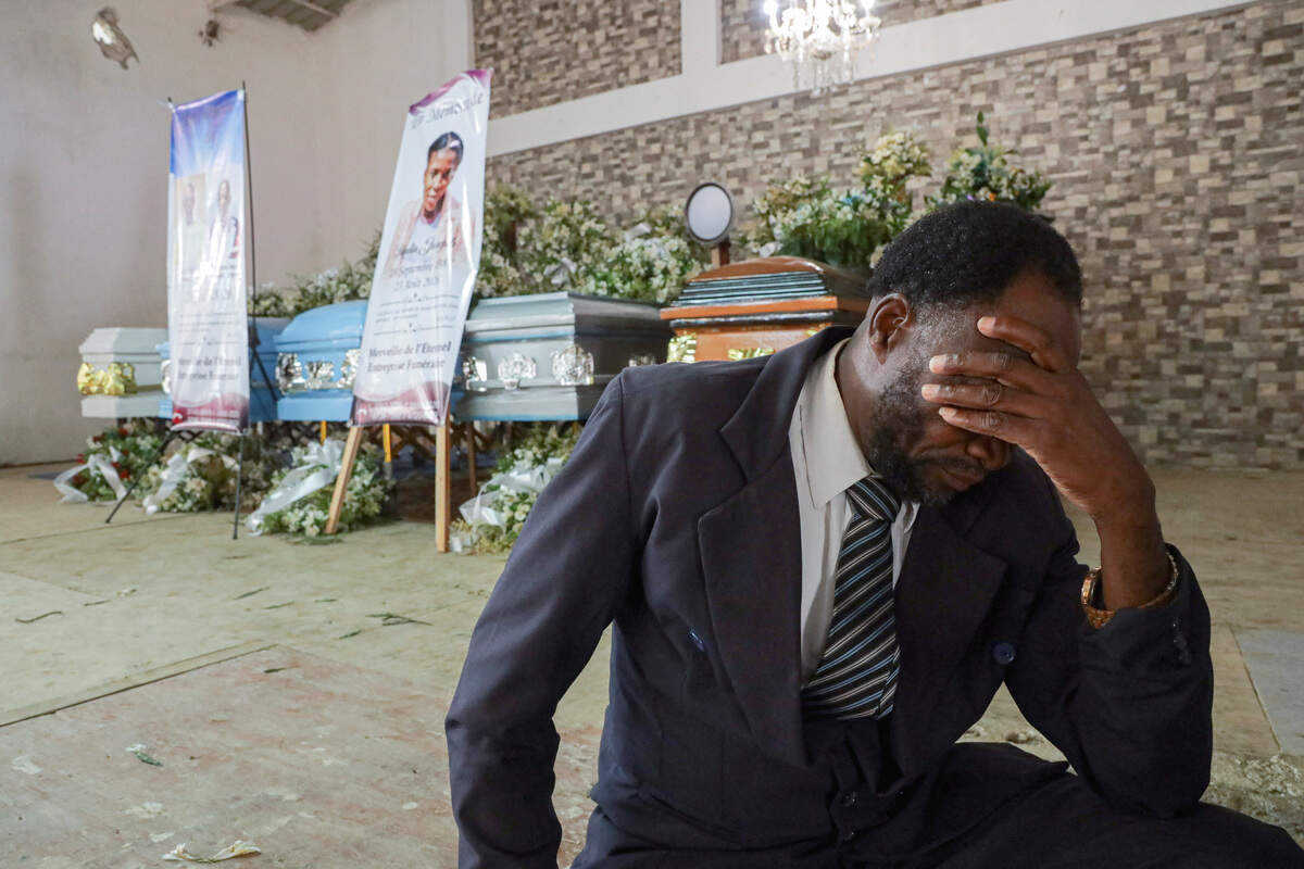 A man mourns in front of caskets during a funeral service for people killed in an armed gang attack on August 23, in Kenscoff, Haiti, Sept. 2, 2026.
