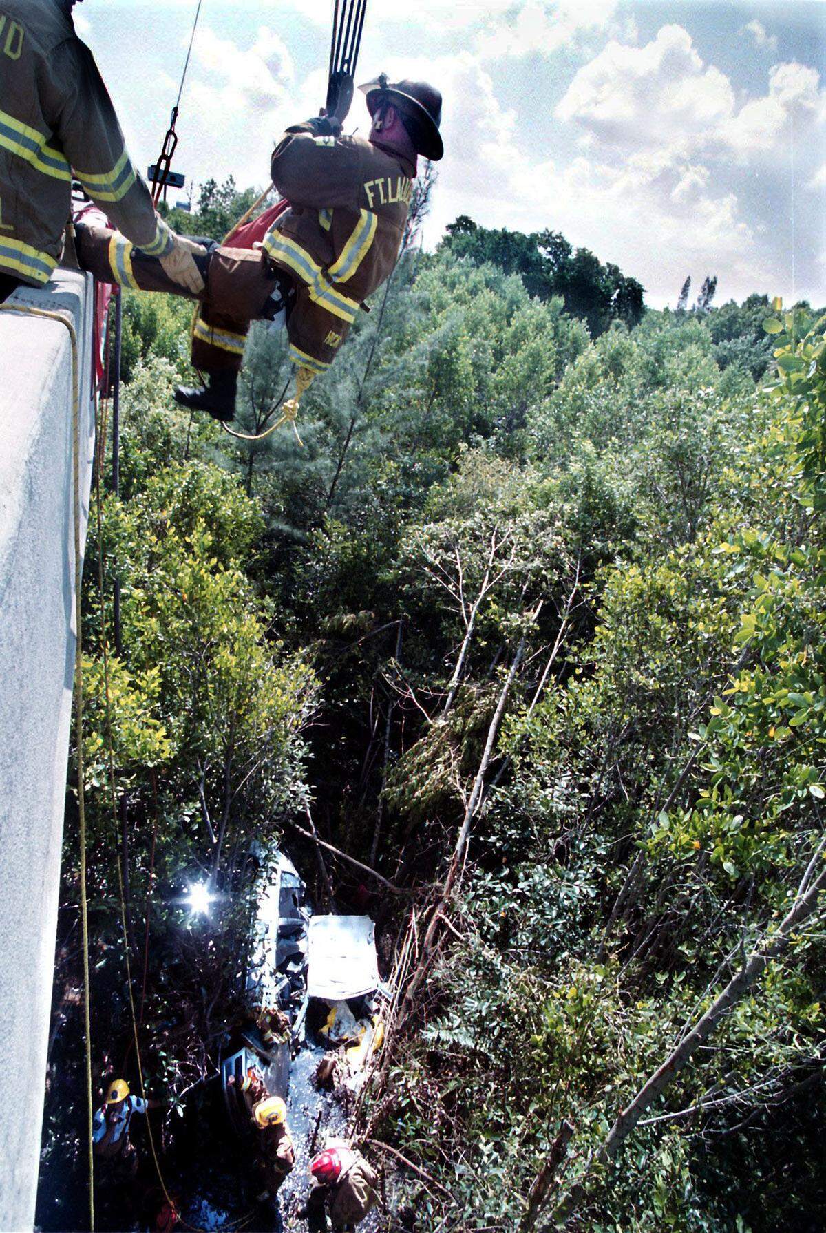 Fort Lauderdale Fire-Rescue Lt. Michael John Hicks, left, rappels up onto a retaining wall of eastbound Interstate-595 after assisting Tillie Tooter, 83, of Pembroke Pines, who was in the car at bottom. Tooter was rescued on a Tuesday; she had been missing since early Saturday, when she was on her way to Fort Lauderdale-Hollywood International Airport to pick up her granddaughter, arriving by jet. Tooter’s Toyota car went over the retaining wall and fell 40 to 50 feet into mangroves and muck. She was conscious when Fort Lauderdale Fire-Rescue firefighter paramedics got to her.