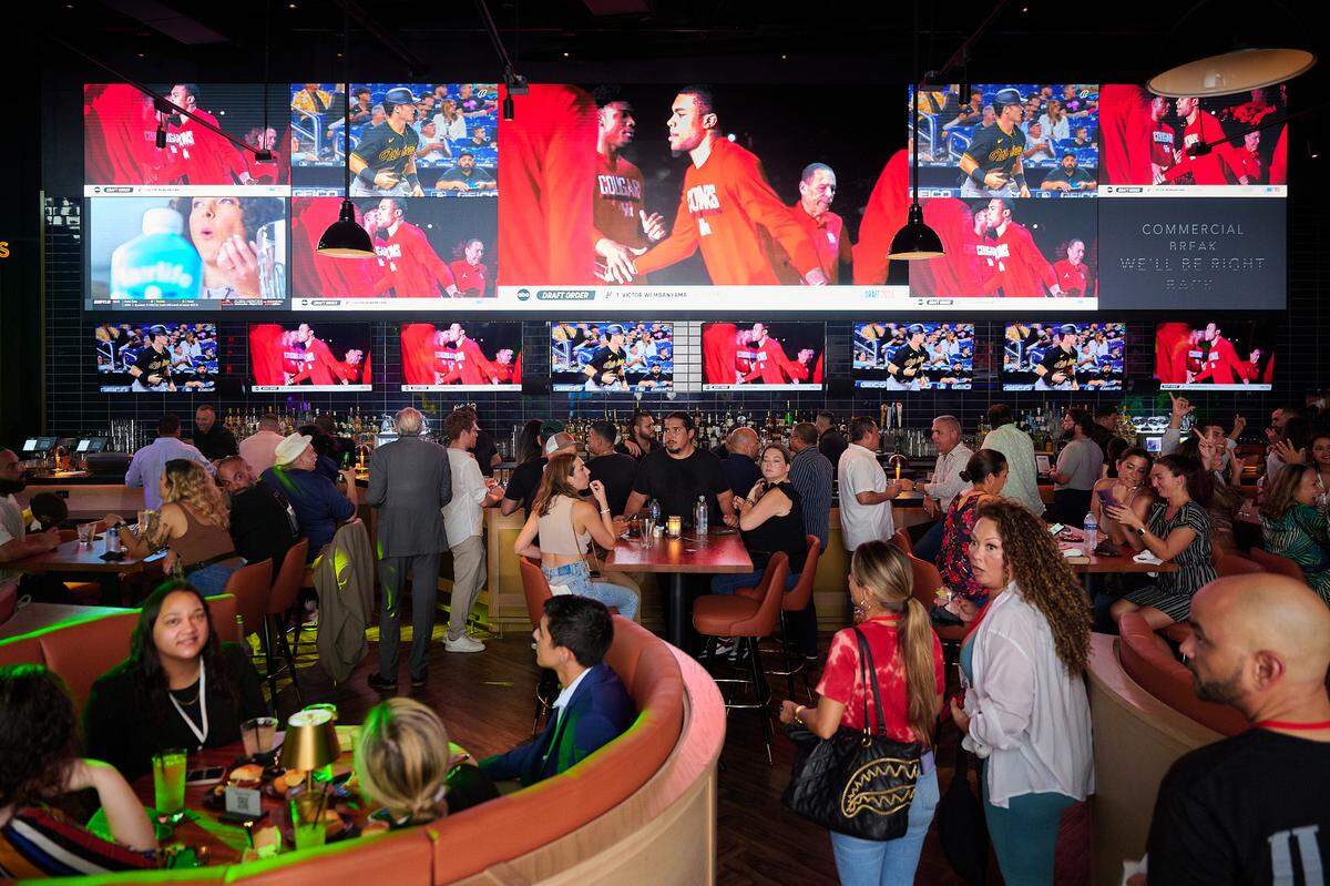 Clientes cenan y beben en Sports & Social, un bar deportivo con entretenimiento en directo y juegos, en Vivo! Dolphin Mall.