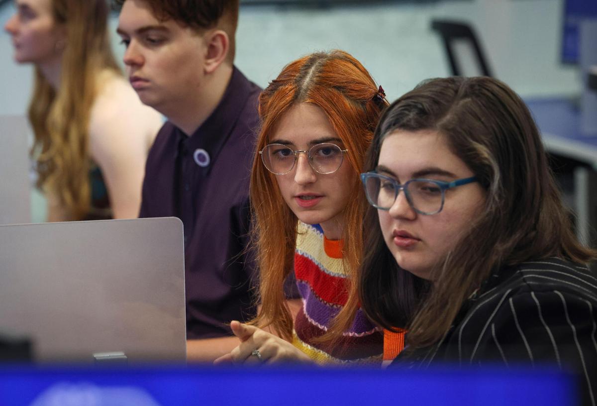 Lea Rabaron, center, and Grace Penza, right, work together to solve a problem during a Miami Dade College class working to use artificial intelligence to spot literary devices in Harry Potter novels. The class convened March 6, at the college’s North campus.