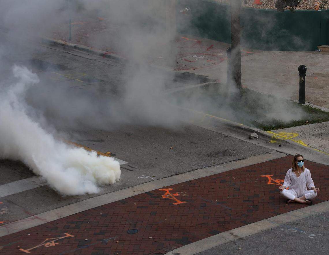 A woman meditates as tear gas is set off around her in downtown Fort Lauderdale during a Justice for George Floyd rally in Fort Lauderdale on Sunday, May 31, 2020.