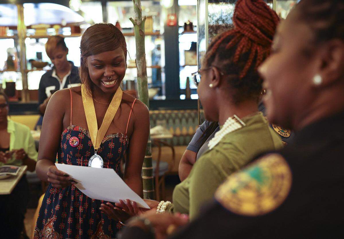 Variah Charles, left, accepts her certificate of completion and a medal during the Teen Talk Dialogue Girl Power session luncheon on Thursday, May 18, 2023, at Red Rooster in Overtown. “Being in Girl Power has made me more extroverted and I really appreciate being around people now,” said Charles during the event.