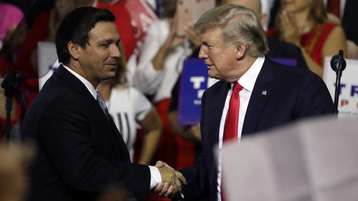 President Donald Trump, right, shakes hands with Florida Republican gubernatorial candidate Ron DeSantis during a rally Tuesday, July 31, 2018, in Tampa.