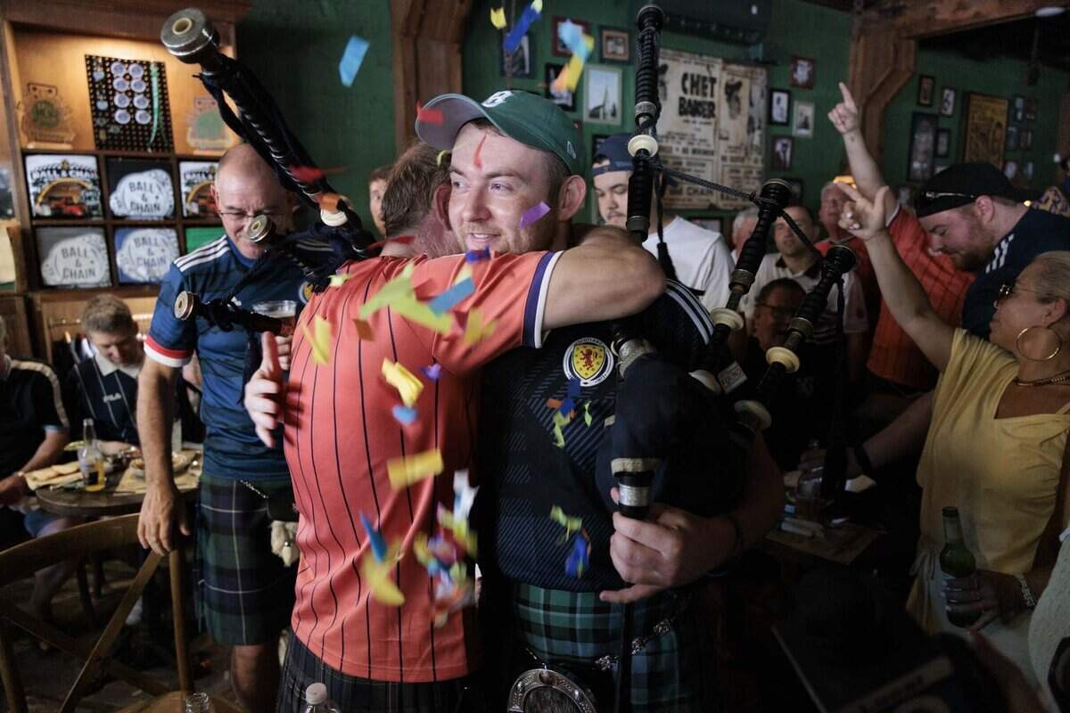 Connor Jardine, right, a bagpiper from Scotland, right, hugs another bag pipe player that he met in a Facebook group of Tartan fans coming to Miami while other Scots sing a song during a gathering of Tartan Army, Scottish National Football team fans, at Ball & Chain on Monday, June 22, 2026, before a parade down Calle Ocho in Miami, Fla.