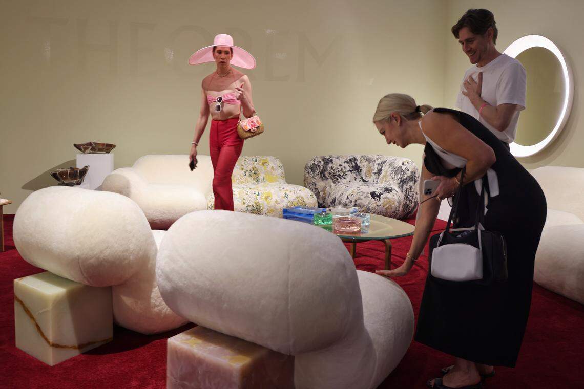 Miami Beach, FL, December 2, 2025 -  Model Di Mondo, left, wearing pink hat, surveys the offerings at Theoreme Editions gallery as Design Miami XX opened its doors during Miami Art Week