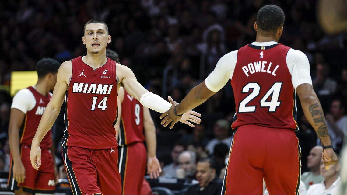 Miami Heat guards Tyler Herro (14) and Norman Powell (24) greet each other on the court during their NBA basketball game against the Milwaukee Bucks at Kaseya Center in Miami on November 26, 2025.