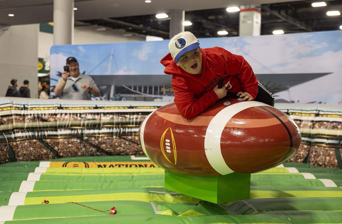 Naftali Hagler, 8, rides a mechanical football while visiting the Playoff Fan Central at the Miami Beach Convention Center on Friday, Jan. 16, 2025, in Miami Beach, Fla. Fans can visit the event ahead of the College Football Playoff National Championship Game between the Miami Hurricanes and the Indiana Hoosiers and enjoy a variety of family-friendly interactive experiences.