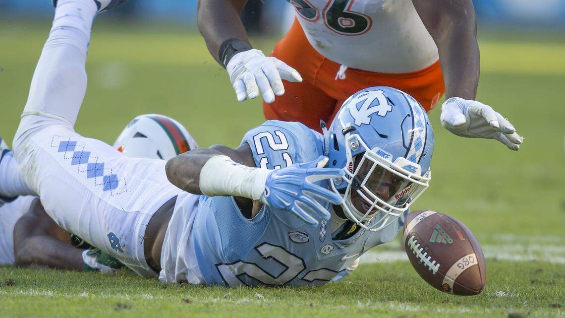 North Carolina's Cayson Collins recovers a fumbled Miami snap in front of Miami's Sunny Odogwu during the first half of an NCAA college football game, in Chapel Hill, N.C., Saturday, Nov. 14, 2015.