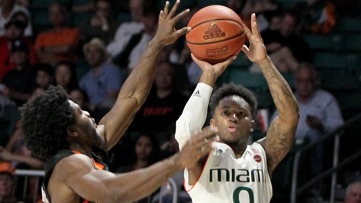 Hurricanes guard Chris Lykes, shoots a three pointer over Camels’ guard Chris Clemons, in the first quarter of the Miami Hurricanes vs Campbell Fighting Camels game at Watsco Center in Coral Gables on Saturday, December 29, 2018.