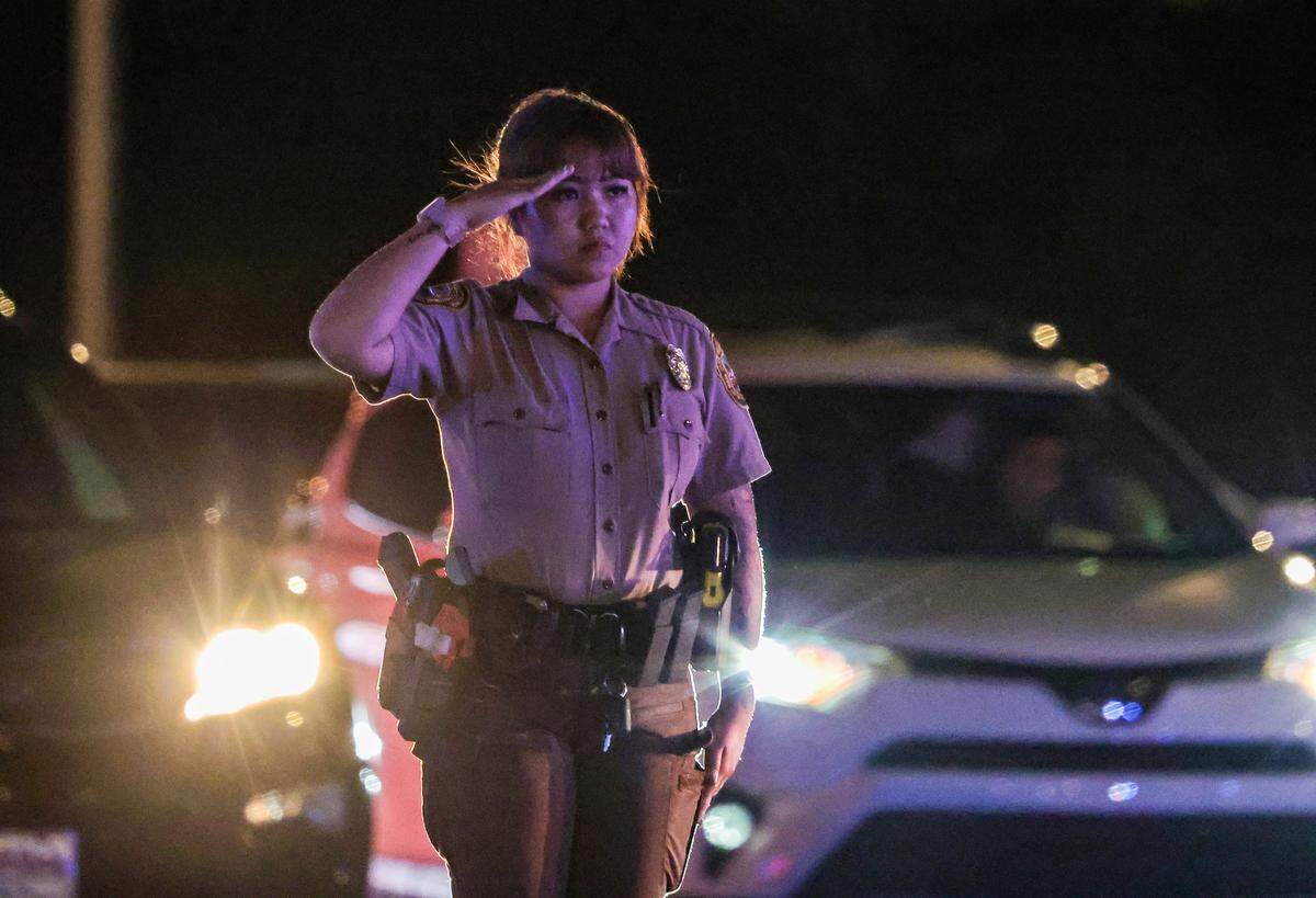 A police officer salutes as the body of Miami-Dade Deputy Devin Jaramillo is escorted by motorcycle officers at HCA Florida Kendall Hospital on Friday. 
