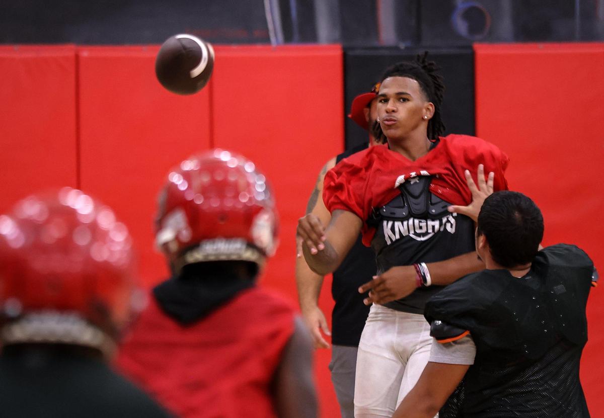 Monarch High football quarterback A.J. Hairston, right, throws a pass while taking snaps as the team held their practice inside the school’s gym due to bad weather and lightning on Monday, July 31, 2023 in Coconut Creek, Florida.