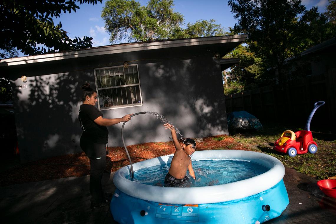 Ledys Cuevas uses a hose to pour water on her son Danny Alvarado, 5, at her home in Miami, on Wednesday, March 18, 2020.