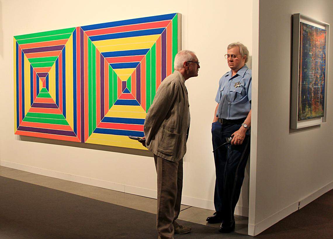 A visitor looks at a piece by artist Duane Hanson next to pieces by Frank Stella, on display at Van De Weghe Fine Art Gallery, from New York, during the invitation only opening of the 10th Art Basel fair at the Miami Beach Convention Center on Wednesday, November 30, 2011.