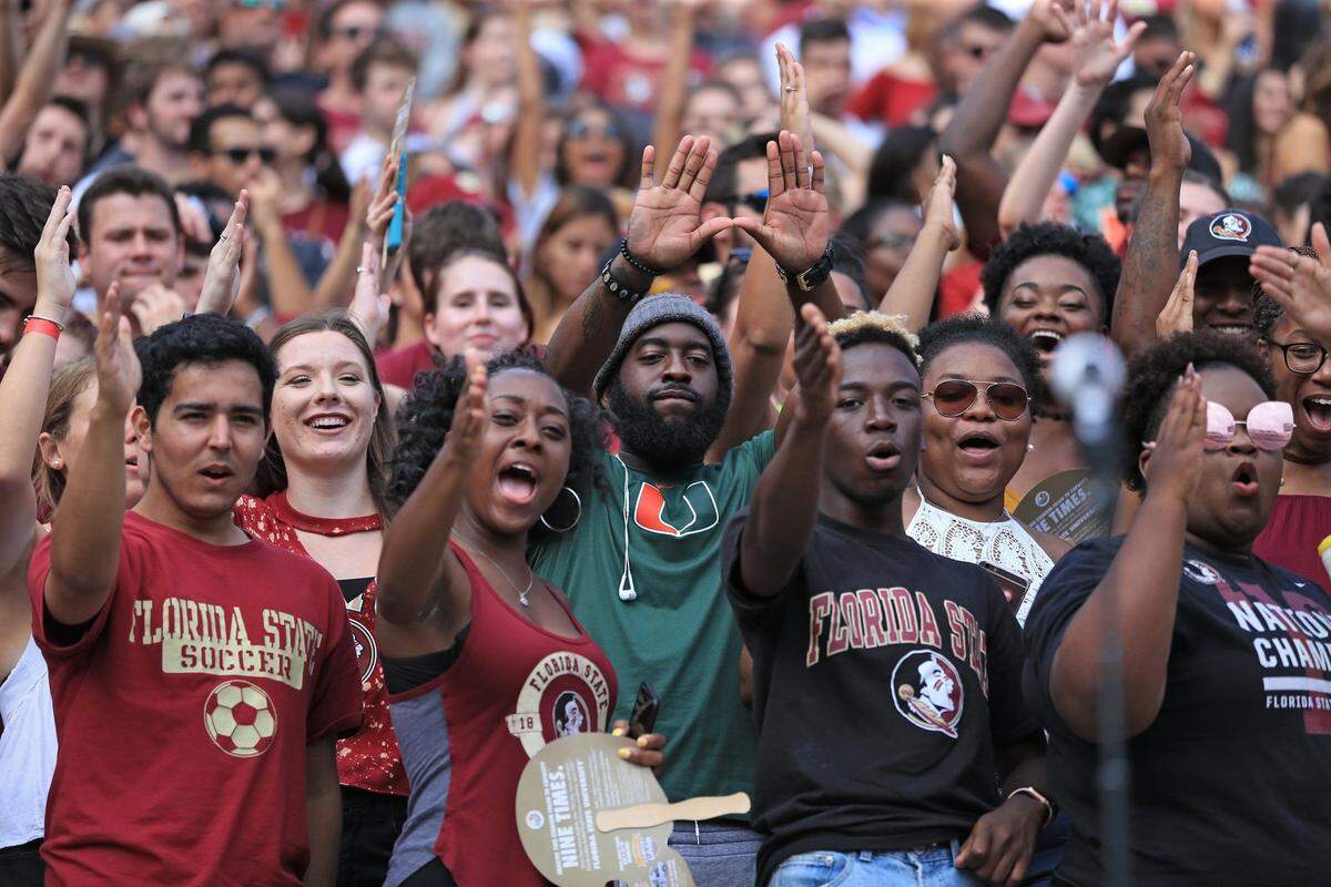 A UM fan flashes the ‘U’ while surrounded by FSU fans doing the Tomahawk chop as the Seminoles host the Miami Hurricanes at Doak Campbell Stadium in Tallahassee on Saturday, Oct. 7, 2017.