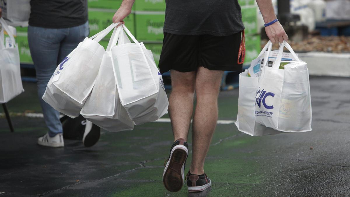 Miami, Florida, September 10, 2020- A volunteer delivers bags of food to a distribution station at the Greater Miami Jewish Federation during a Kosher Food Distribution Drive-Thru Event . While the drive-thru is open to all in need, it is a unique opportunity for members of the Jewish community who follow strict kosher dietary laws to receive items like Kosher ground meat, frozen meals, as well as locally grown fruits and vegetables.
