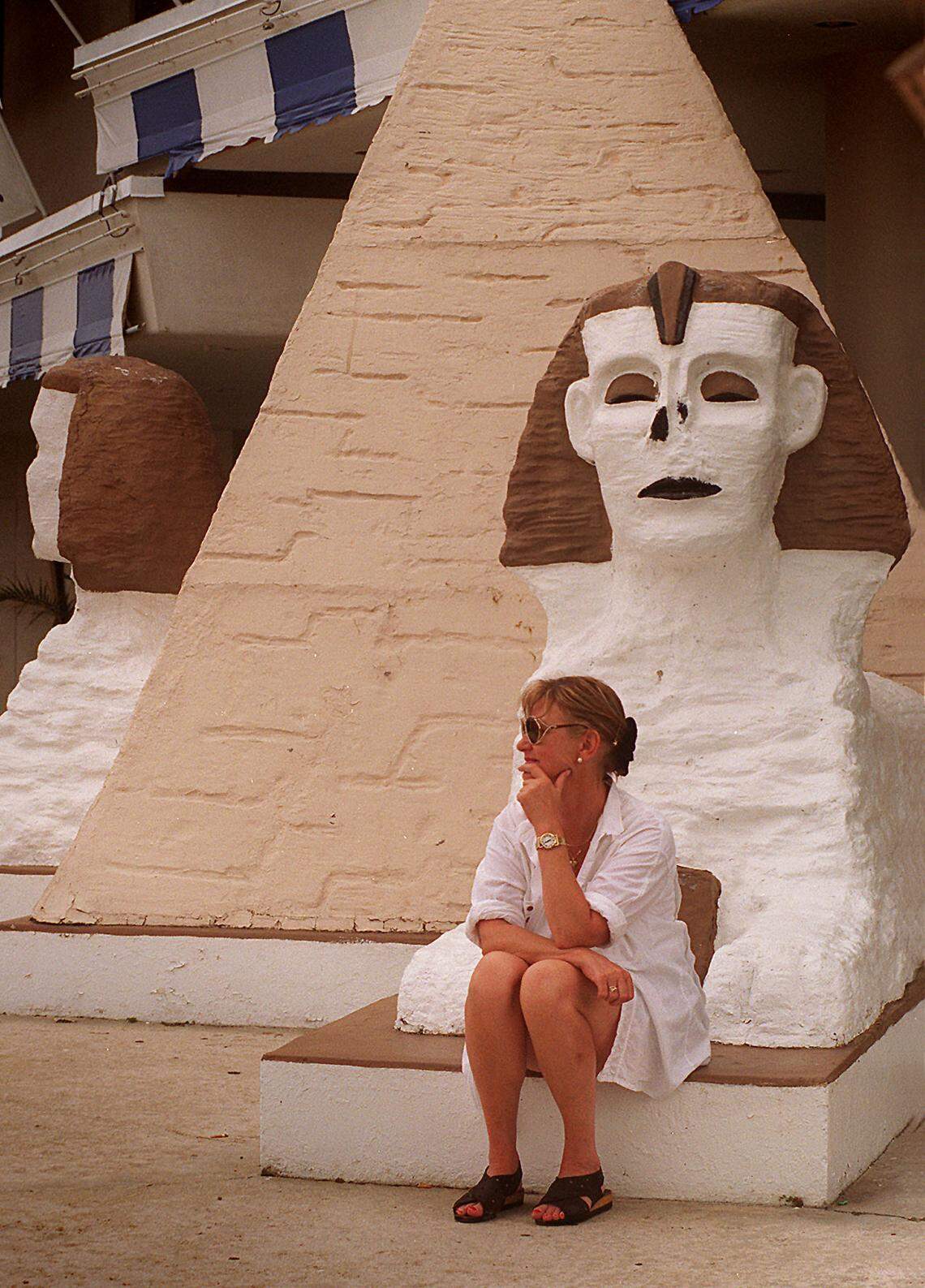 In a 1996 photo, a German tourist sits near one of the two sphinxes that once decorated the front of the Suez hotel.
